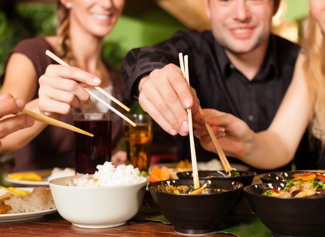 les gens qui mangent de la nourriture thaïlandaise et chinoise avec des baguettes à une table