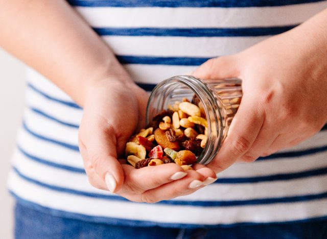 mains versant un pot de noix et de fruits secs